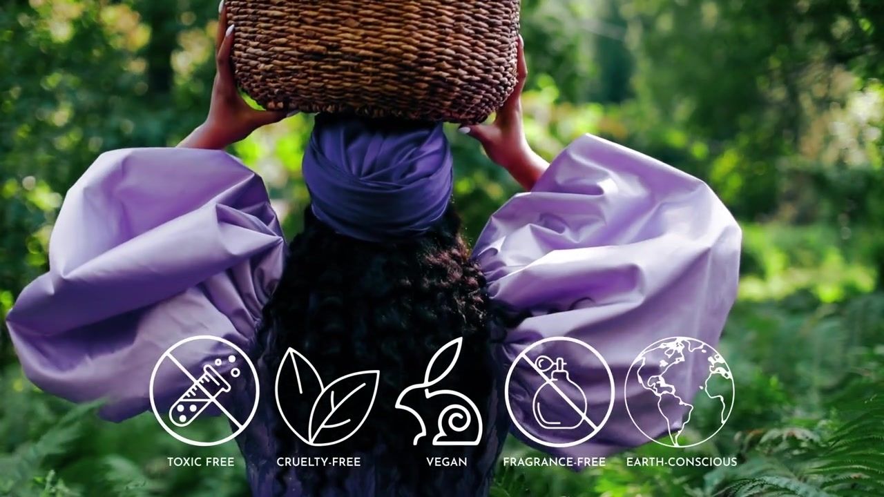 Women of color wearing purple and holding a round woven basket above head. Toxic-free, fragrance-free, vegan, cruelty-free, earth-conscious. 